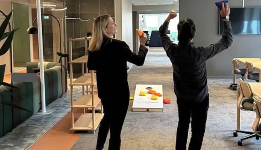 Employees playing cornhole during team building at the office